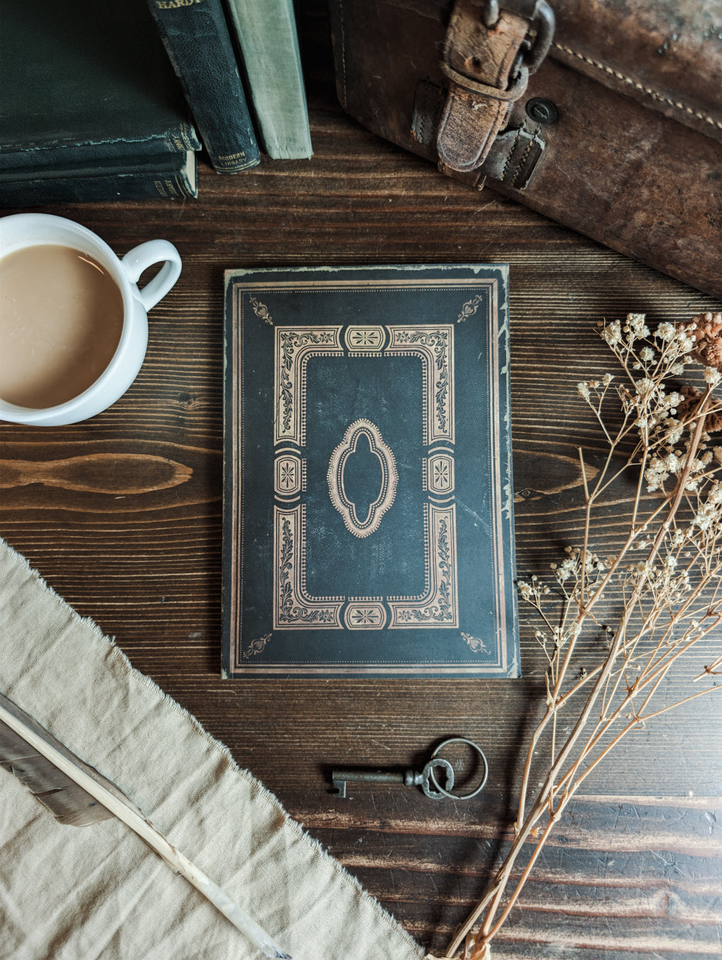 an open book of a floral dnd journal and a gold embossed book cover next to a sprig of leaves