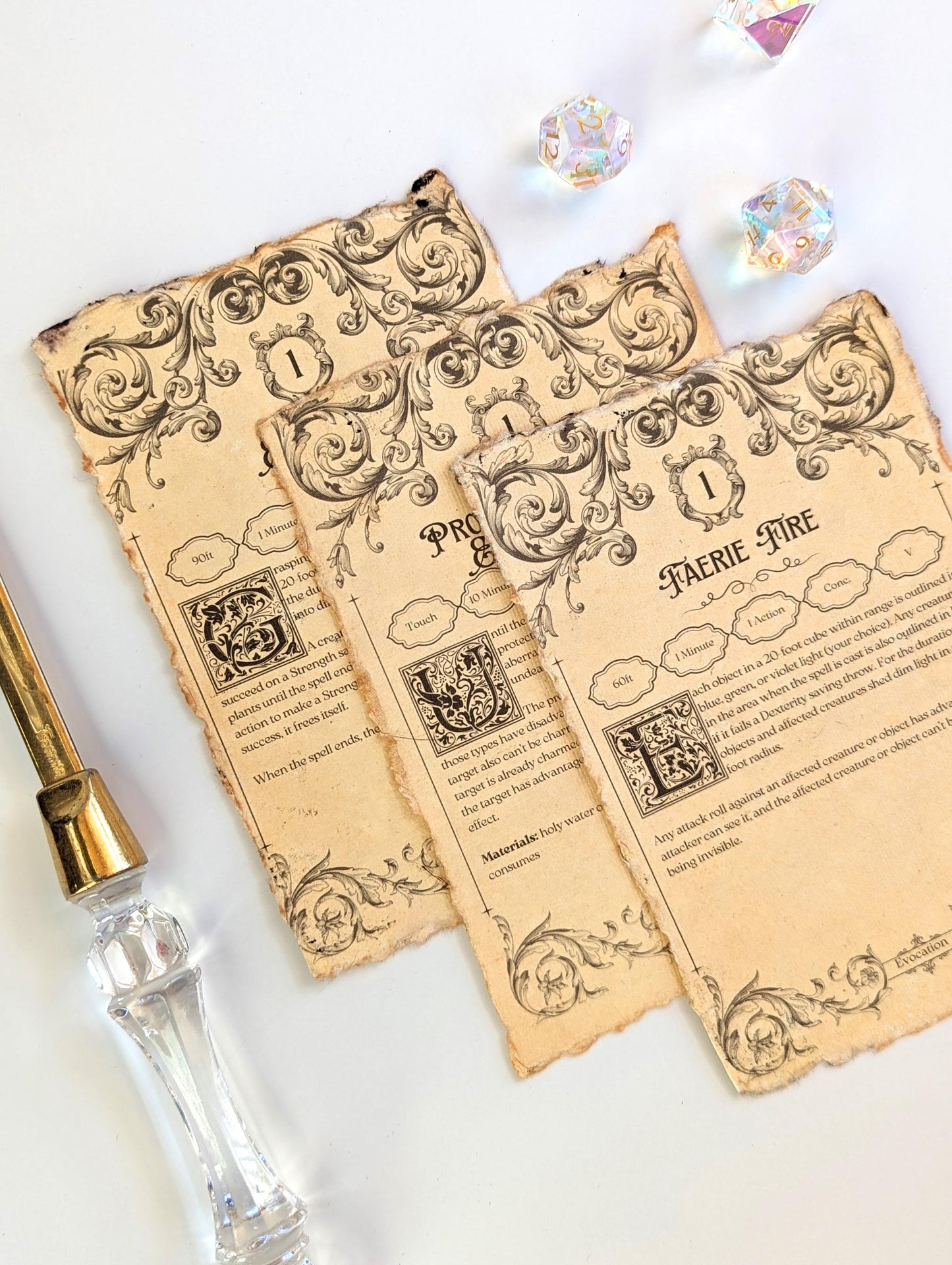 Decorative dnd spell cards with intricate designs and text next to dice and letter opener