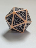 Close-up of The relic D20 with ornate black detailing and parchment-colored edges