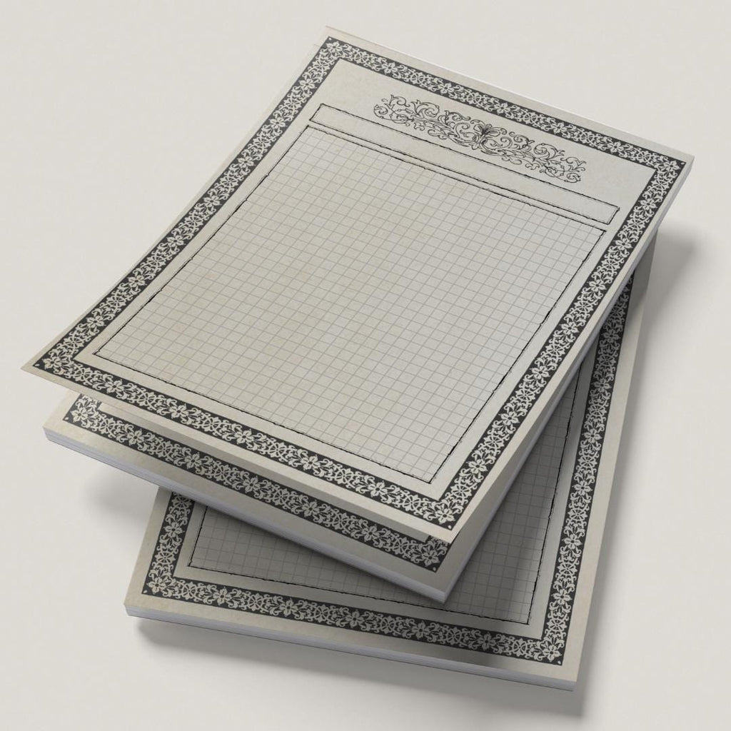 Stack of map pads with grid and decorative border on a light gray background