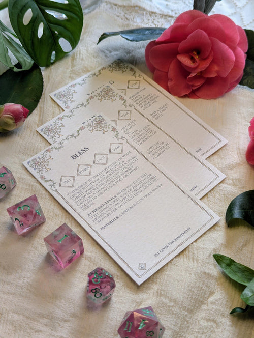 Printed dnd spell cards next to dice and flowers