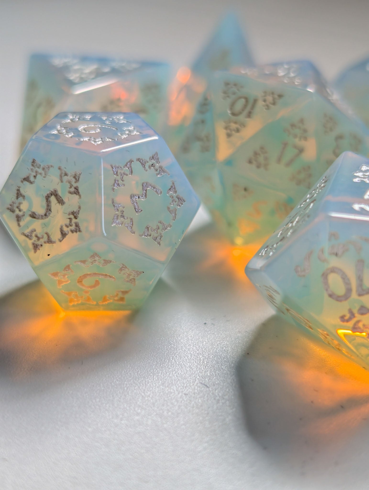 Close-up of The Moonveil opalite D&D dice showing pale blue, pearl, and warm reflective tones