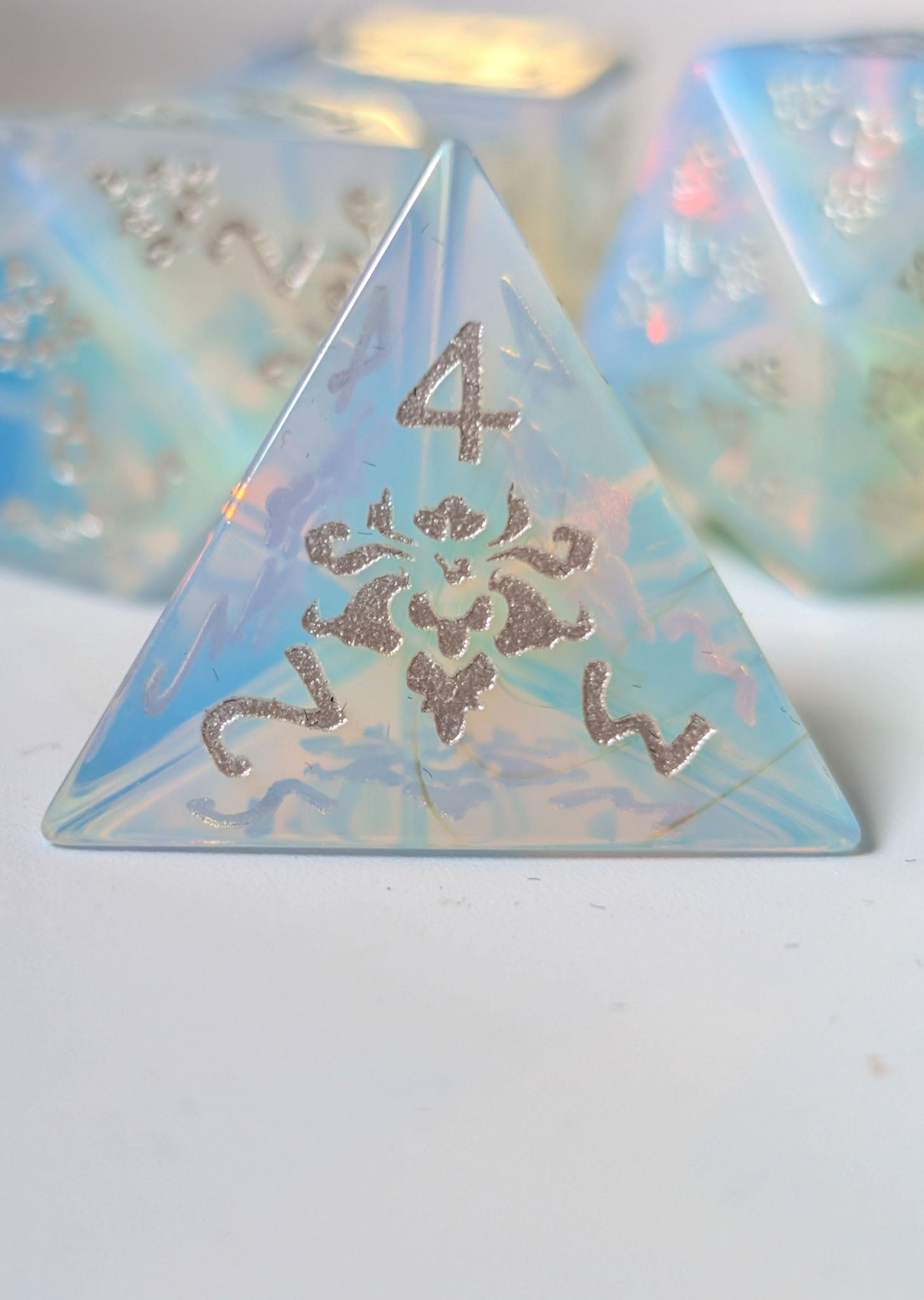 Close-up of The Moonveil opalite D4 showing its translucent blue finish and decorative silver details