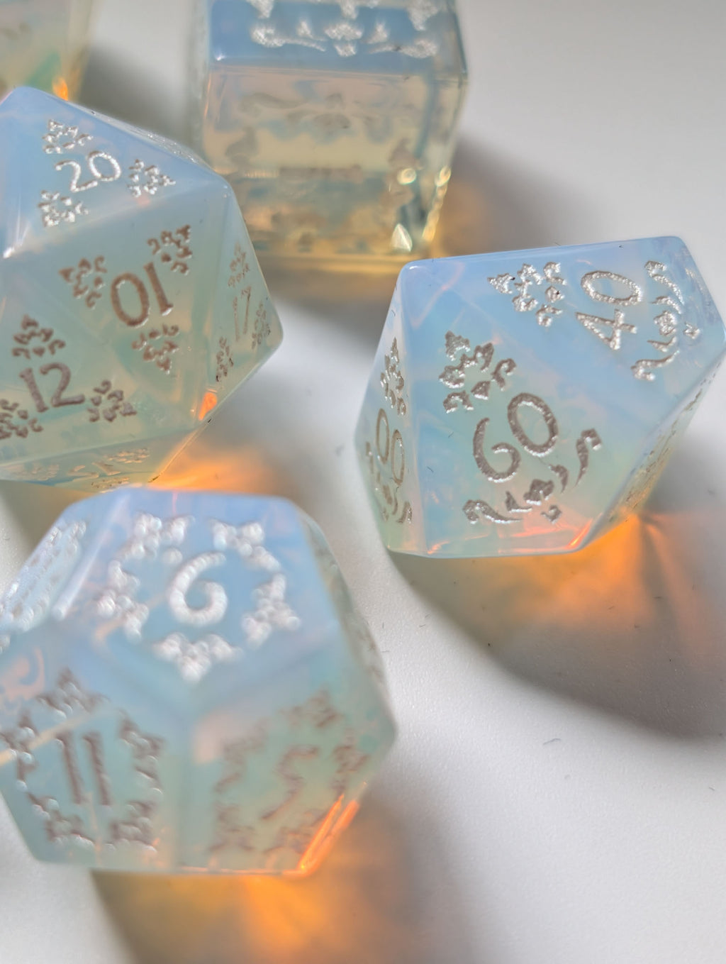The Moonveil opalite D&D dice showing ornate silver numbers against a translucent blue finish