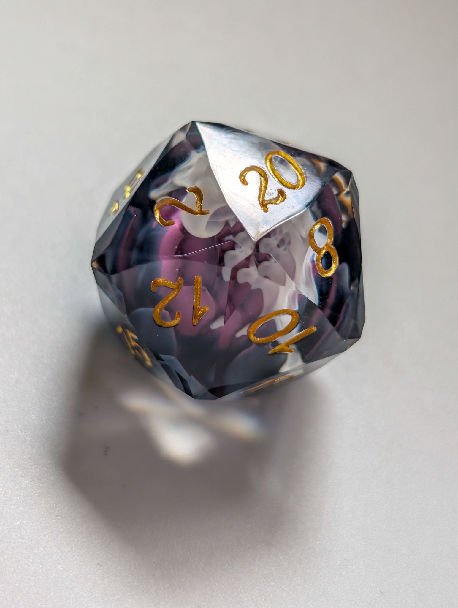 Close-up of The Nightbloom D20 with multifaceted gemstone cut, dark floral inclusions, and gold numbering