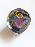 Close-up of The Nightbloom D4 showing its multifaceted cut and dark flower inclusion