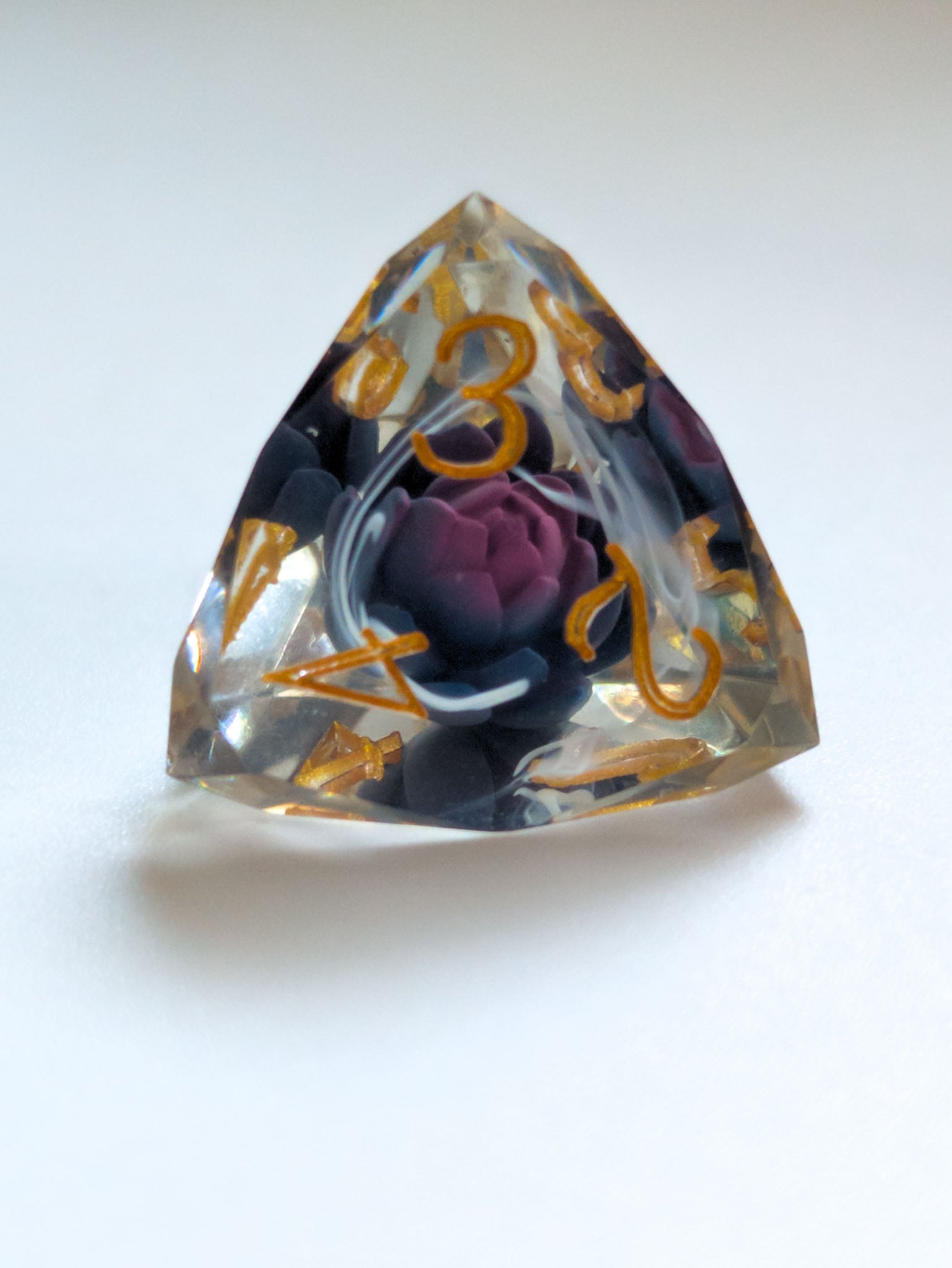 The Nightbloom gemstone-cut D&D die with suspended dark floral detail and metallic gold numbers