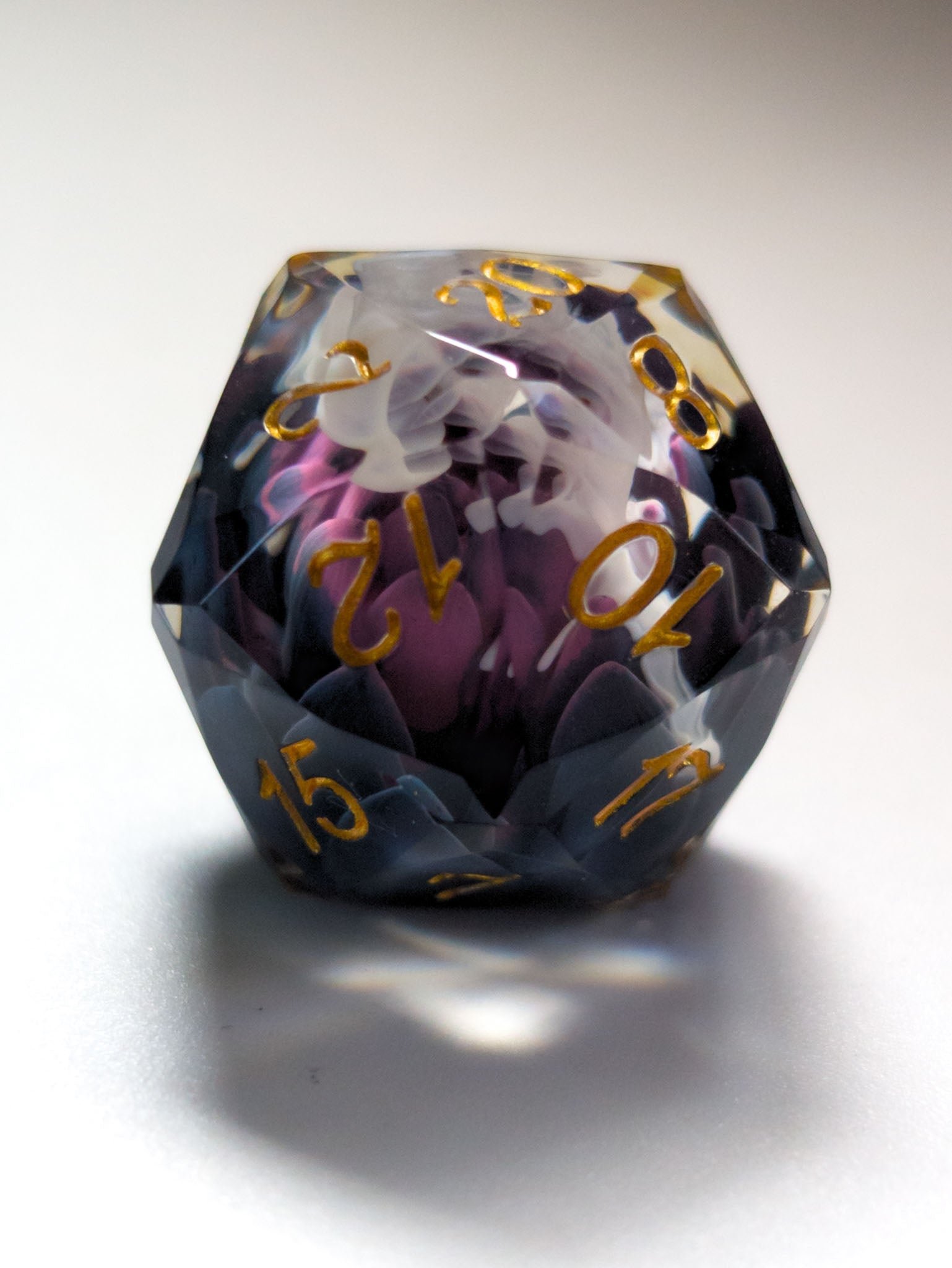 Close-up of The Nightbloom D&D die showing faceted edges, dark floral inclusions, and gold numbering