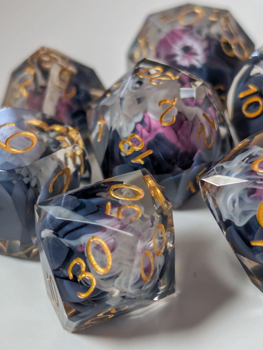 Detail view of The Nightbloom gemstone-cut polyhedral dice with smoky purple flowers and gold numbers