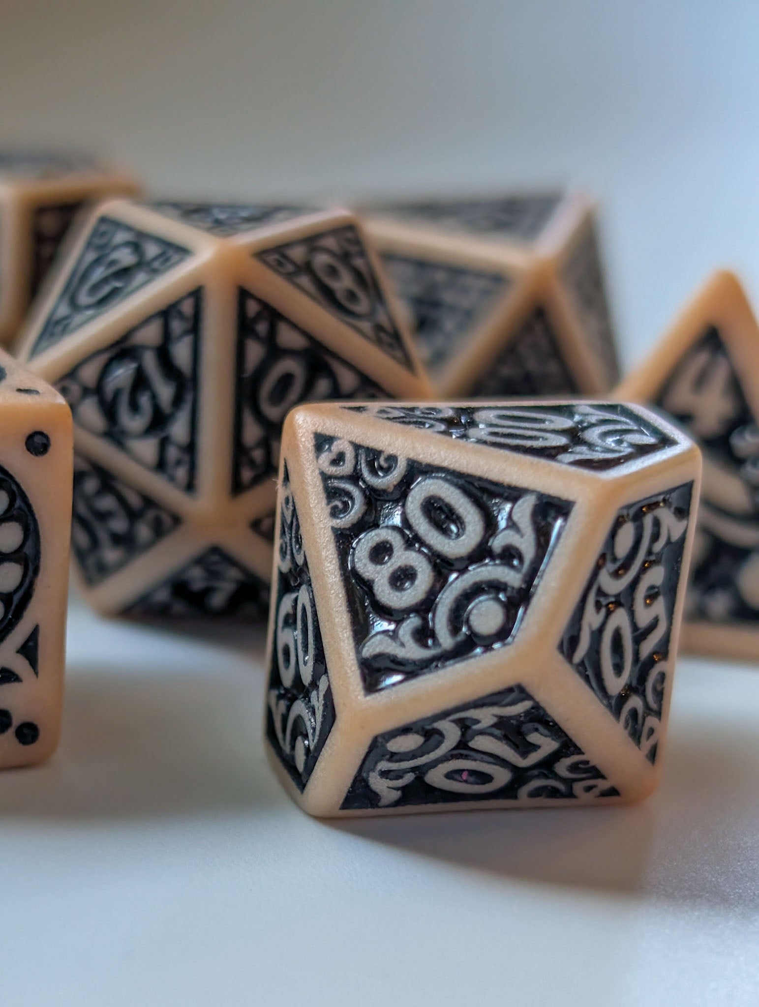 Close-up of The Relic polyhedral dice showing intricate black number and border details