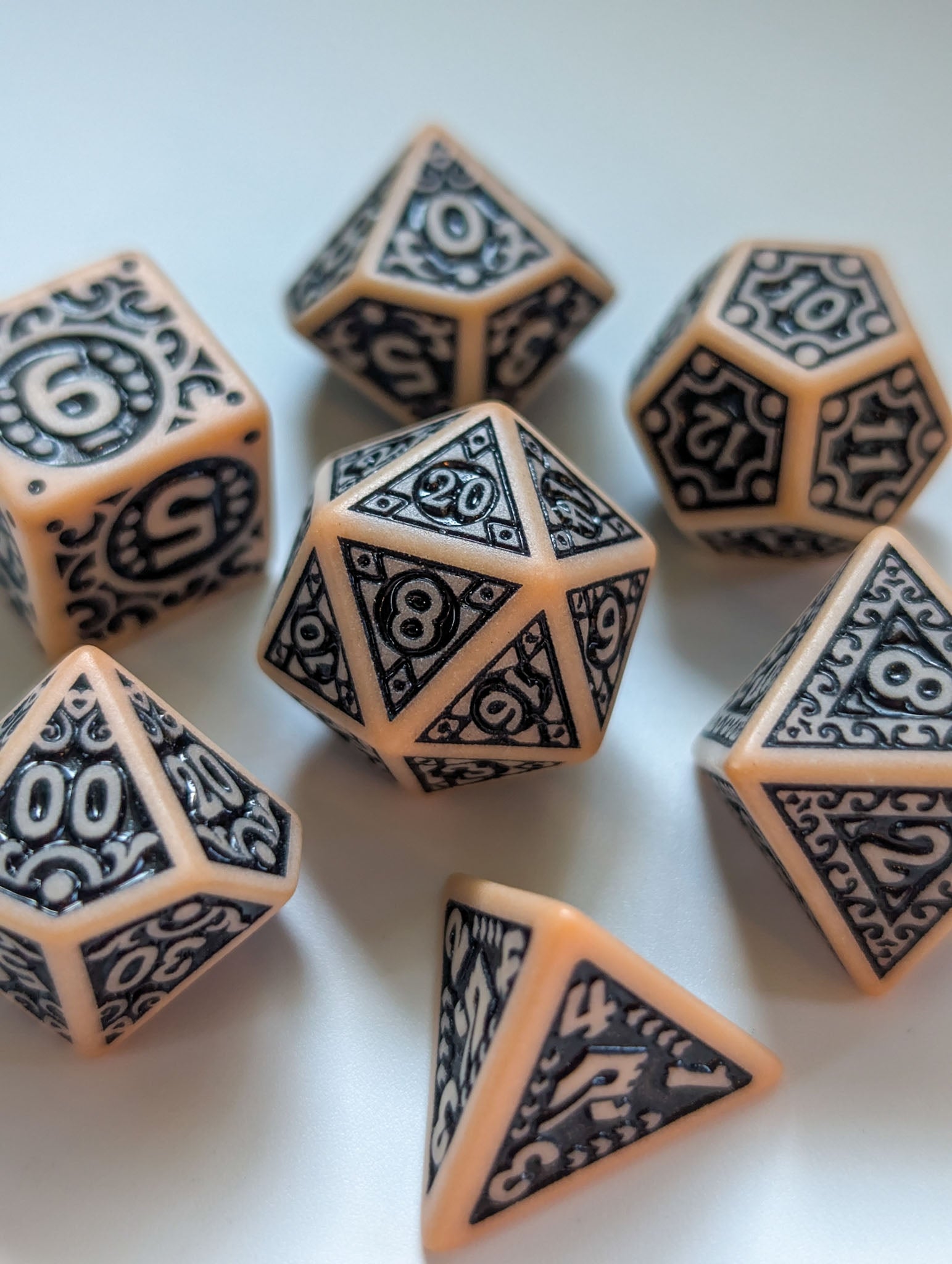 Angled view of The Relic 7-piece D&D dice set with ornate black designs