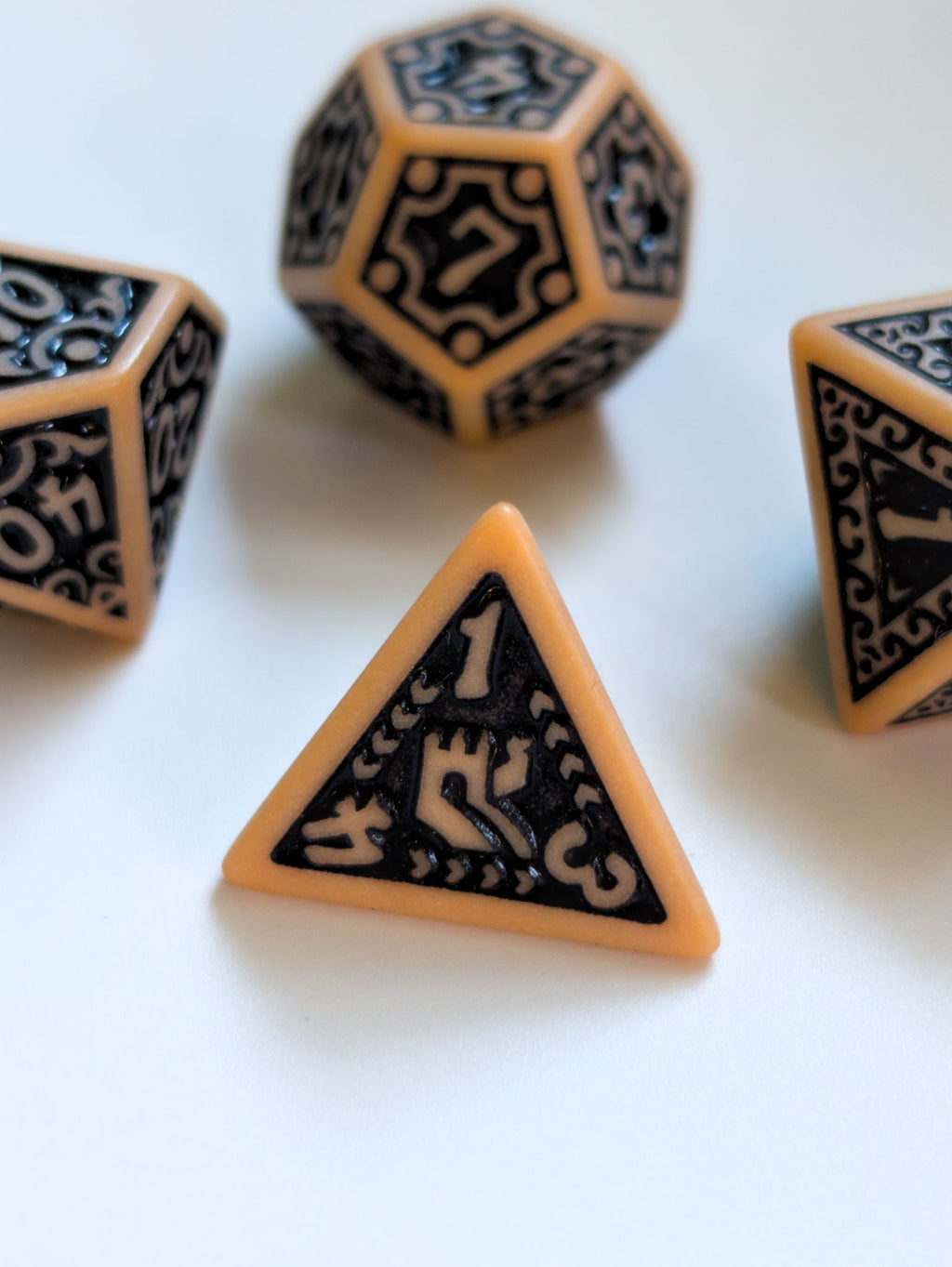 The Relic D4 displayed with matching ornate parchment and black polyhedral dice
